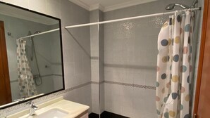 Ein Badezimmer mit Dusche, Waschbecken und Spiegel.