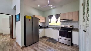 A modern kitchen with stainless steel appliances, light wood cabinets, and a herringbone-patterned floor.