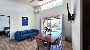 A living room with a blue sofa, a wooden dining table, and a ceiling fan.