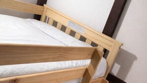 Ein Etagenbett mit Holzbettgestell und weißer Bettwäsche.