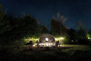 A dome-shaped structure with a table and chairs in front, surrounded by trees and a starry night sky. - Luxe King Geodome Tobermory Glamping South (Miller Lake)