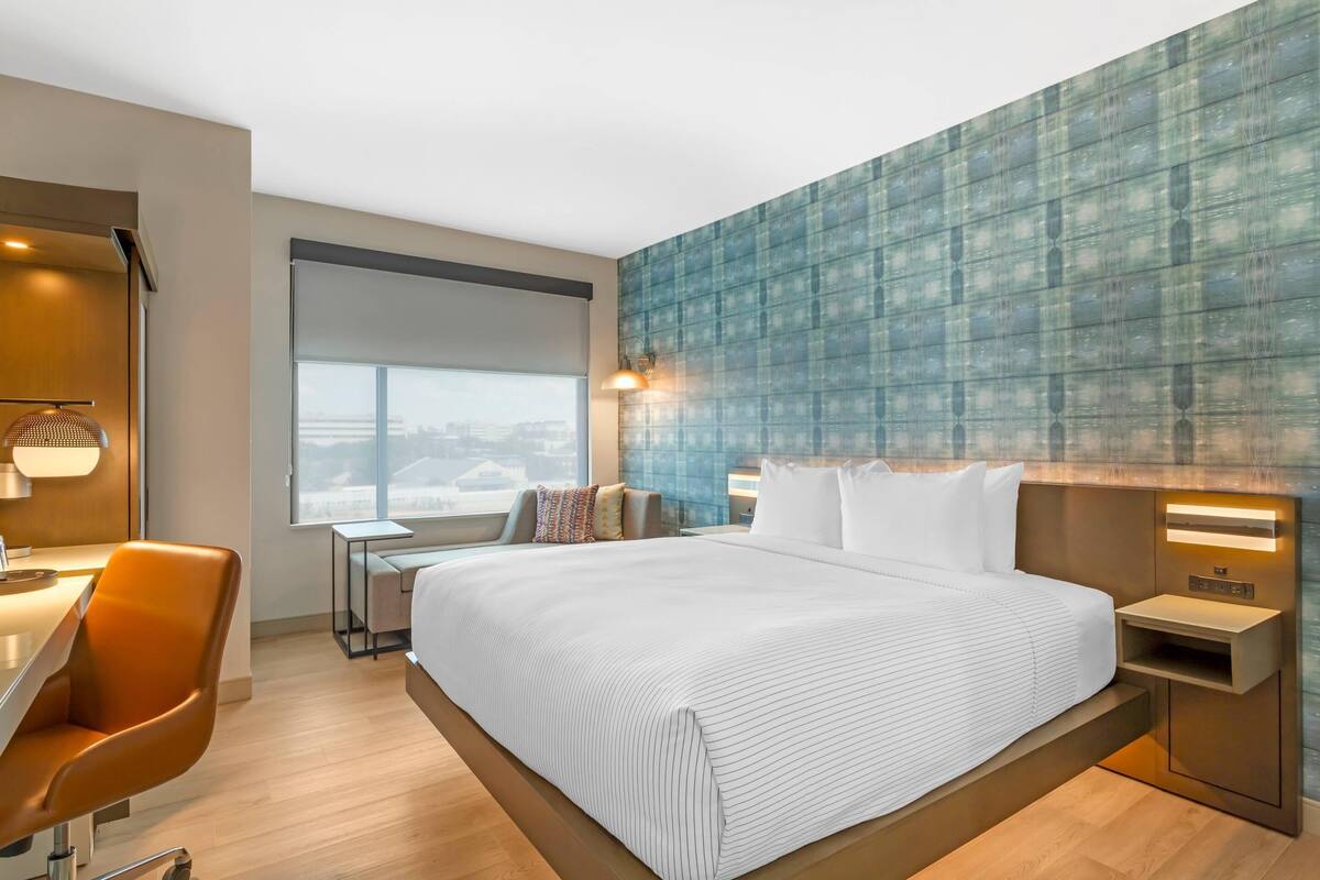 Une chambre d’hôtel moderne avec un grand lit, un bureau et une chaise.