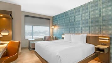 Una habitación de hotel moderna con una cama grande, un escritorio y una silla.