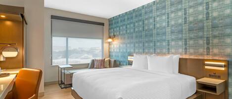 Una habitación de hotel moderna con una cama grande, un escritorio y una silla.