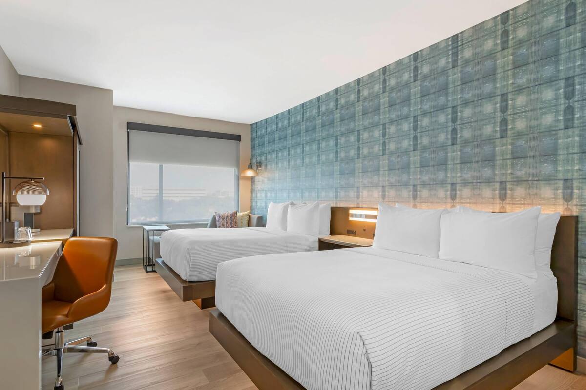 Une chambre d’hôtel avec deux lits, un bureau et une chaise.