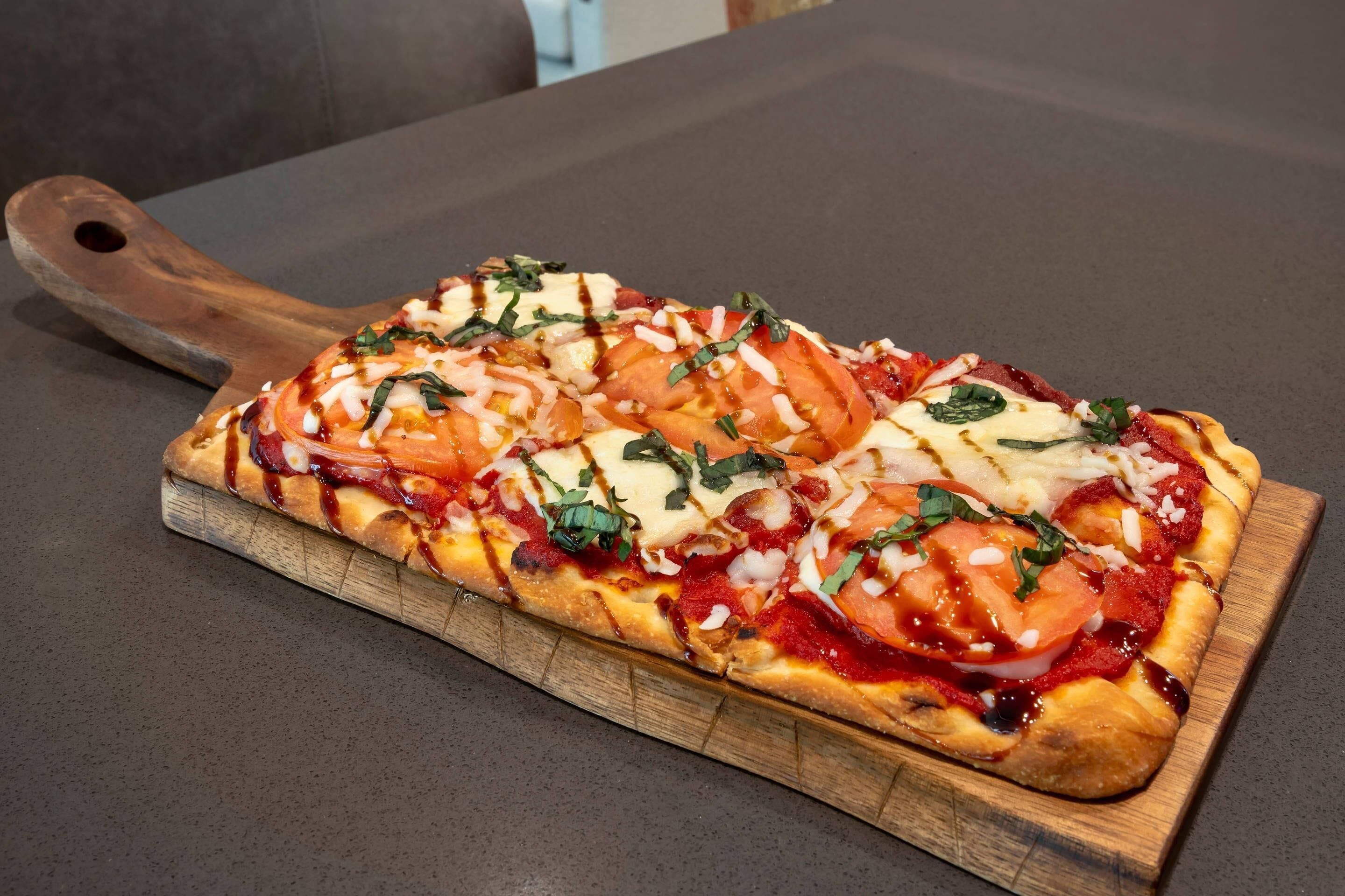 Een pizza op een houten plank.