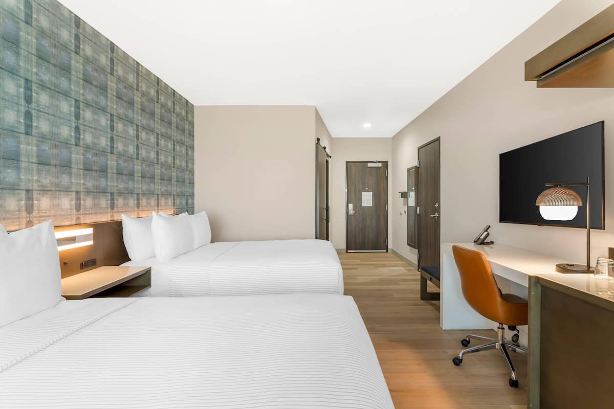 Une chambre d’hôtel avec deux lits, un bureau et une chaise.
