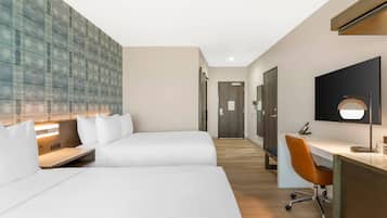 A hotel room with two beds, a desk, and a chair.