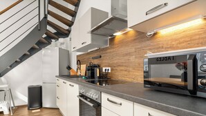 A modern kitchen with white cabinets, a built-in stove, and a microwave.