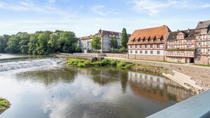 A riverside view with traditional half-timbered buildings and a calm water body.