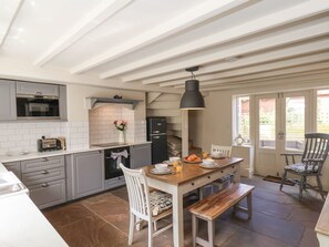 A kitchen with grey cabinets, a black oven, and a wooden dining table with chairs.