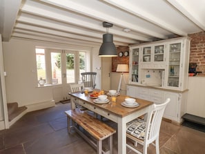 A kitchen with a wooden table set for breakfast, white cabinets, and a brick wall.