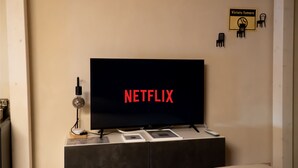 Een televisie waarop 'NETFLIX' staat, een wandlamp en een klein bordje met 'Vietato fumare' (niet roken).