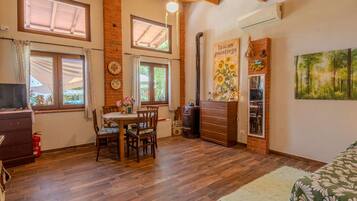 A cozy room with a wooden ceiling, a dining table with chairs, a dresser, and a painting of sunflowers.