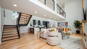 Amplia sala de estar con escaleras, cocina y comedor.