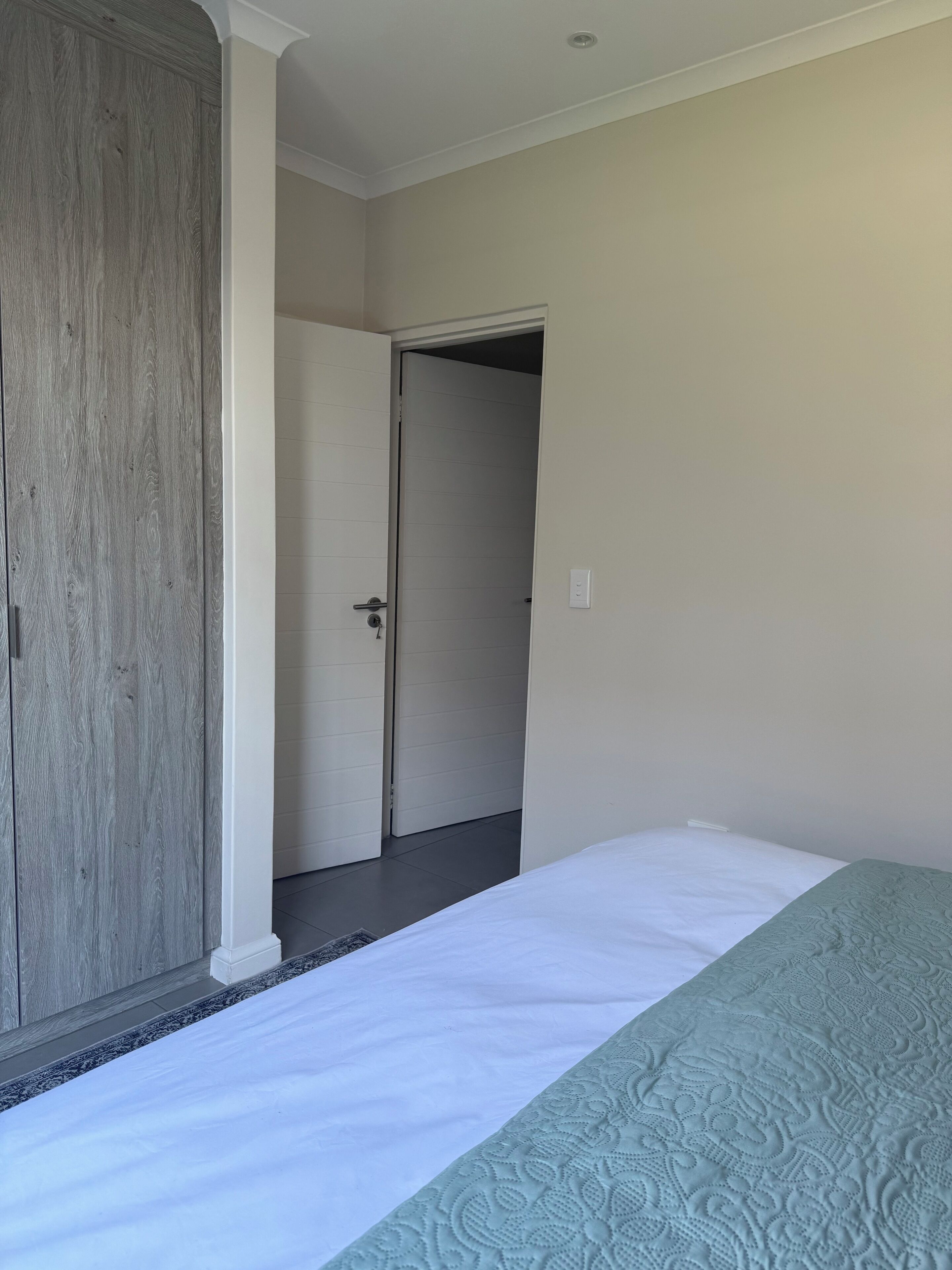 Ein Hotelzimmer mit einem Bett, einem Kleiderschrank und einer Tür zu einem anderen Raum.