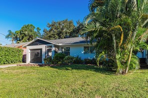 A single-story house with a front porch, a garage, and a well-maintained lawn. - Charming 2-bedroom house in welcoming Sarasota with AC (Sarasota)