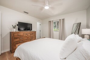 A bedroom with a bed, a TV on a wooden dresser, a ceiling fan, and a window with curtains. - Charming 2-bedroom house in welcoming Sarasota with AC (Sarasota)