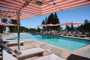 A pool area with striped umbrellas, lounge chairs, and a clear blue pool.