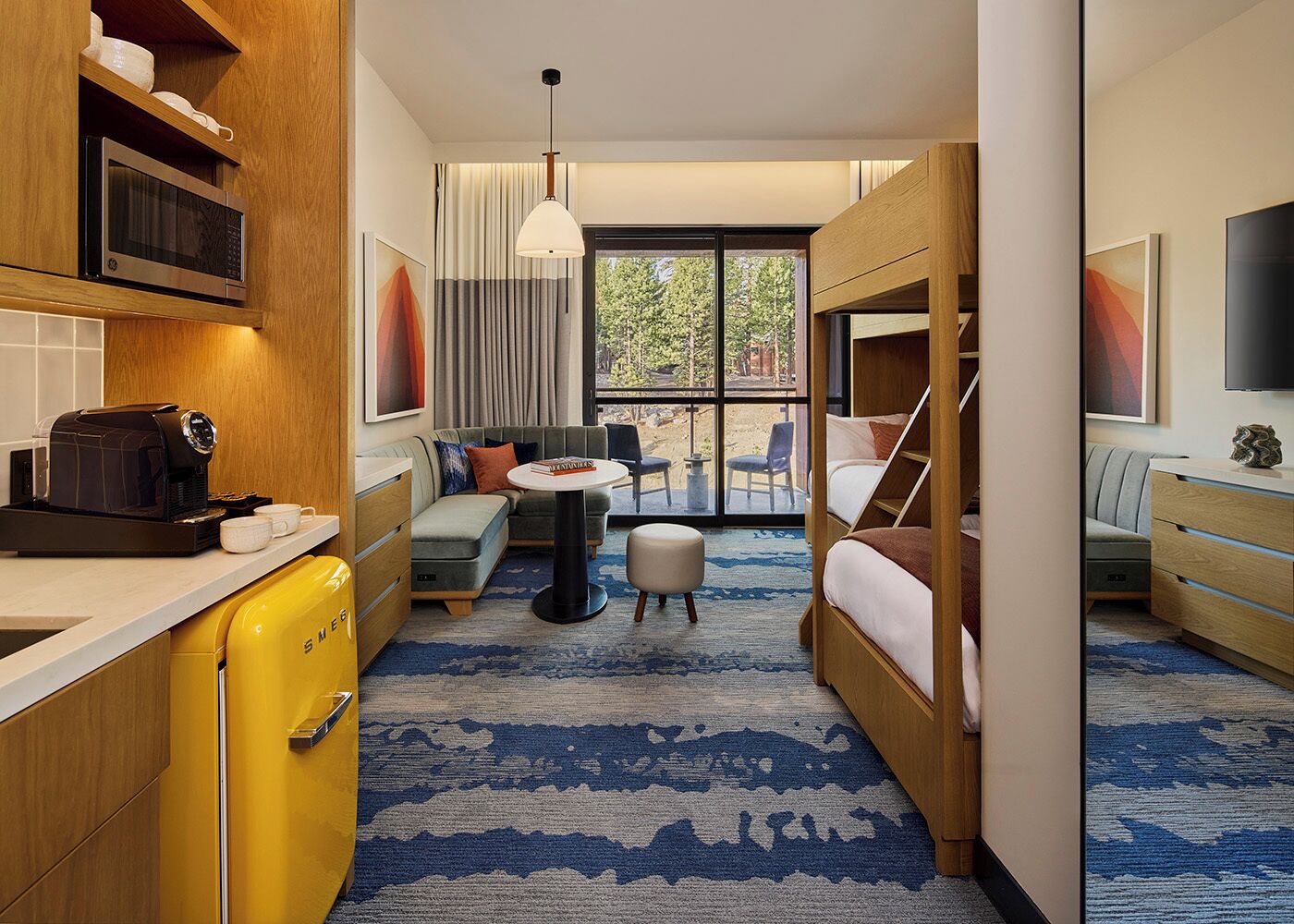 Una habitación de hotel compacta con kitchenette, un sofá, una mesita redonda y una cama.