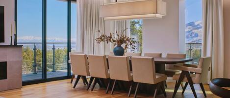 A modern dining area with a table, chairs, and a vase of dried flowers.