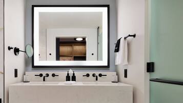 Une salle de bain moderne avec un grand miroir, deux lavabos et un porte-serviettes.