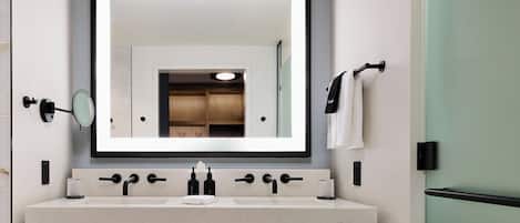 A modern bathroom with a large mirror, two sinks, and a towel rack.