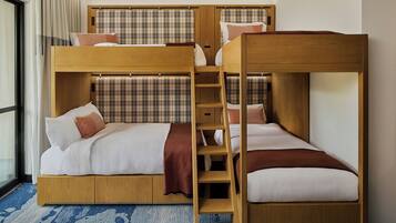Dormitorio con literas, una escalera de madera, cabecero a cuadros y una alfombra azul estampada.