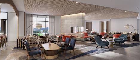 A modern hotel lobby with a central seating area, a fireplace, and large windows offering a view.