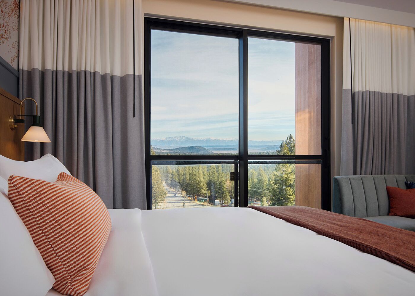 Une chambre d’hôtel avec un grand lit, un canapé et une vue sur une forêt et des montagnes.