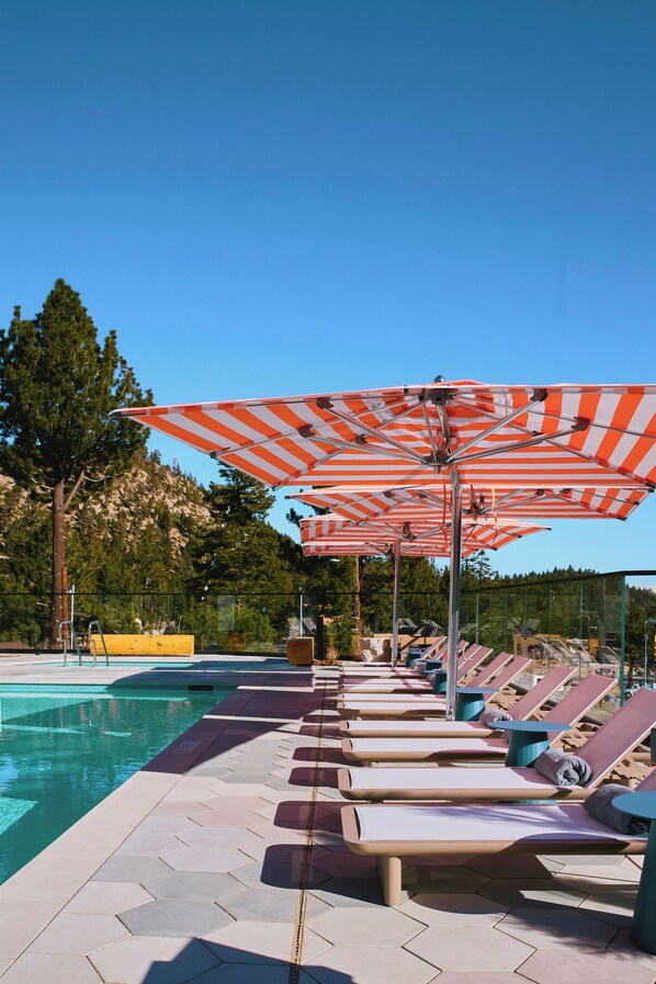 A poolside area with sun loungers and striped umbrellas.