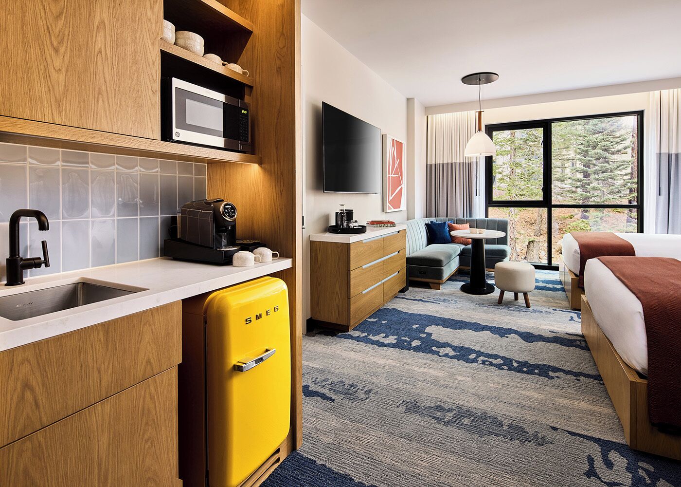 Une chambre d’hôtel moderne équipée d’un coin cuisine, d’un canapé, d’une petite table ronde et d’un lit.