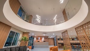 Un hall d’hôtel moderne, doté d’un design circulaire, comprenant un comptoir d’accueil, un espace salon et un escalier.