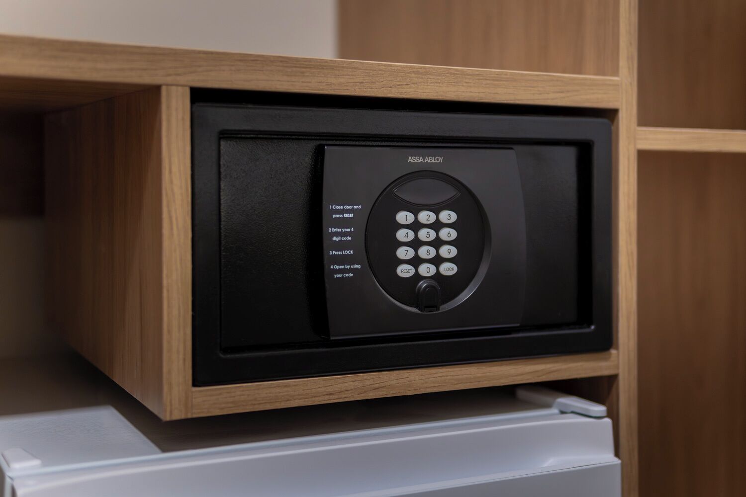 A black electronic keypad with instructions for use, mounted on a wooden cabinet.