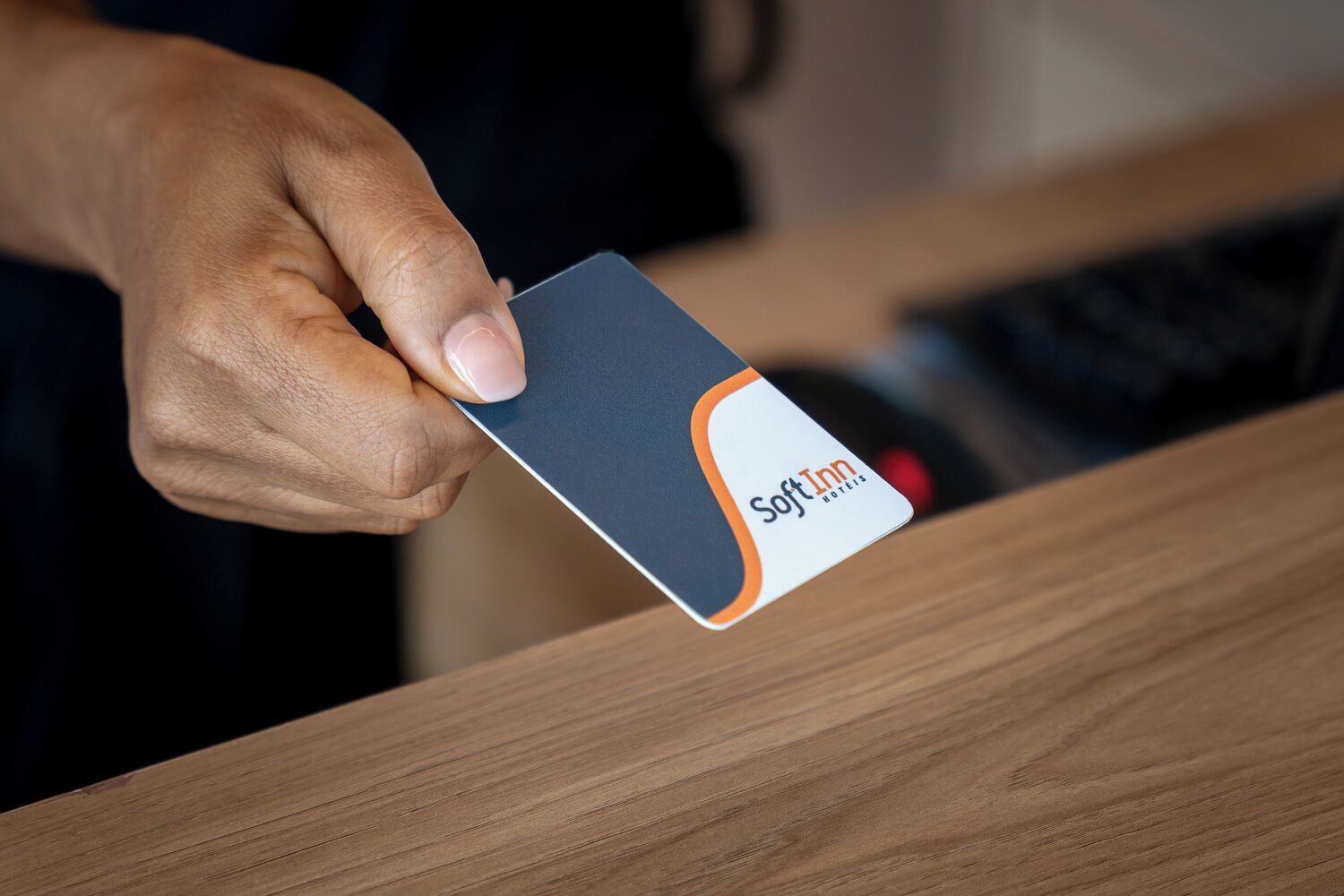 Una mano sosteniendo una tarjeta con el logotipo de 'Soft Inn Hotels'.