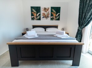 A double bed with a wooden frame, white bedding, and two towels on each side. There are three wall-mounted paintings of plants above the bed. - Apartments Sweet Escape - Two Bedroom Apartment with Terrace and Sea View (Dubrovnik)