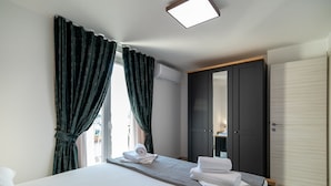 A hotel room with a bed, a wardrobe, and a window with curtains. - Apartments Sweet Escape - Two Bedroom Apartment with Terrace and Sea View (Dubrovnik)