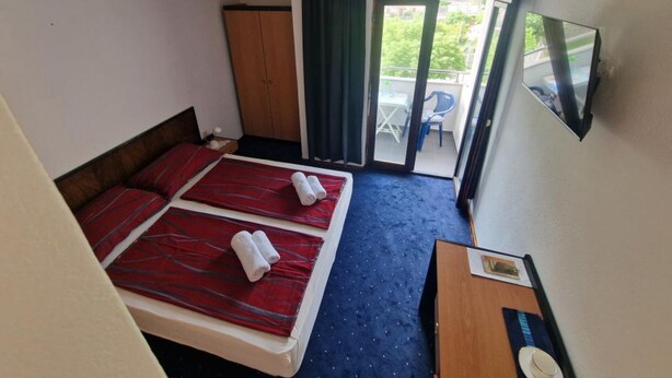 A hotel room with two beds, a TV, a desk, and a balcony with a table and chairs. - Rooms by Robi Novigrad - Double room with Balcony 3 (Novigrad - Zadar)