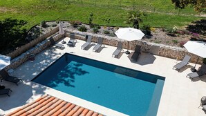 A rectangular swimming pool with a tiled deck, surrounded by lounge chairs and umbrellas. - Les Genêts - PMR gîte - pets welcome (Saint-Christophe-du-Bois)