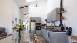 A modern kitchen with grey cabinets, a built-in oven, and a coffee machine. - Les Genêts - PMR gîte - pets welcome (Saint-Christophe-du-Bois)