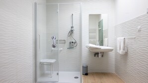 A modern bathroom with a glass-enclosed shower, a white sink, and a wooden floor. - Les Genêts - PMR gîte - pets welcome (Saint-Christophe-du-Bois)