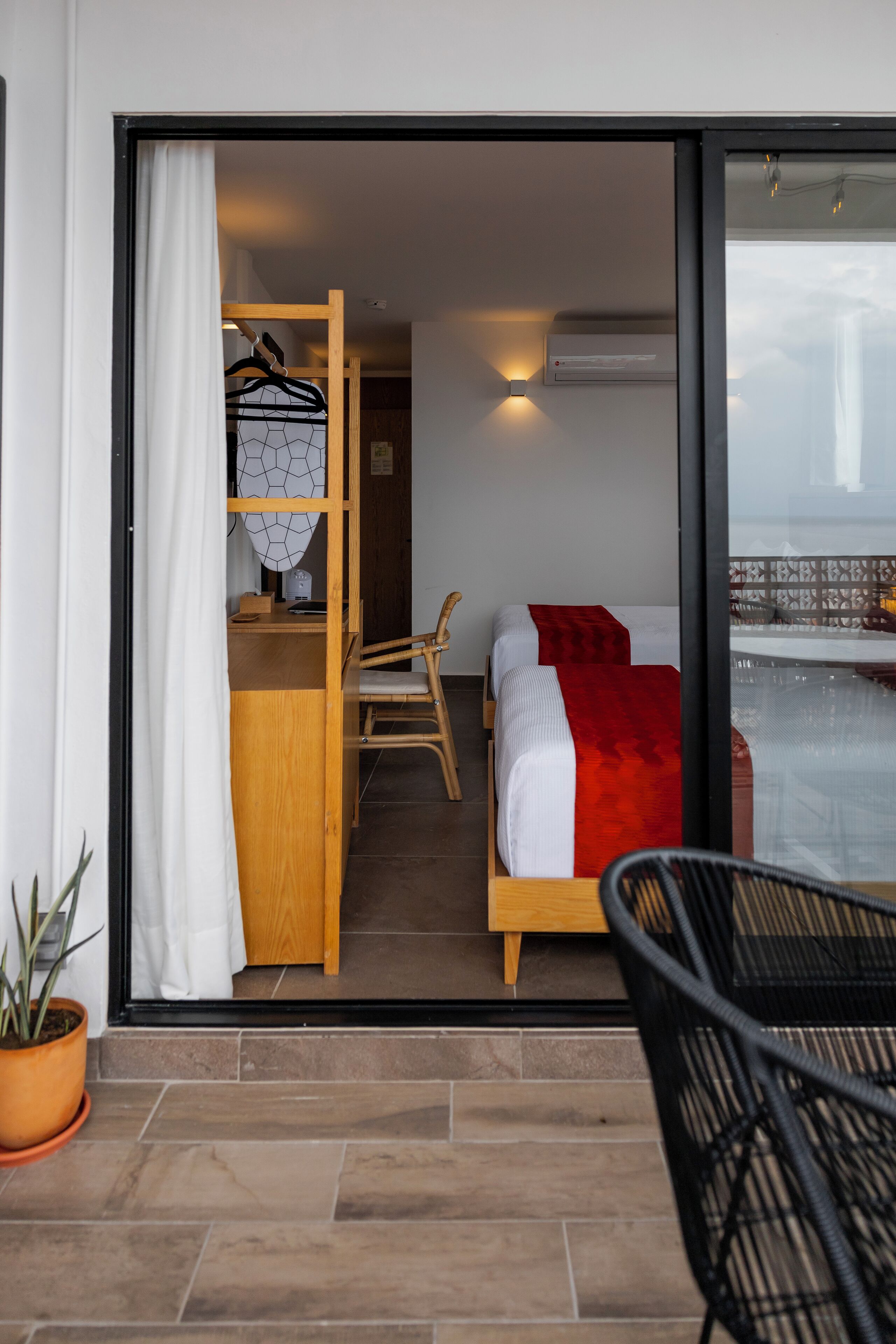 A room with a bed, a desk, and a chair. There is a window with a view of the outside.