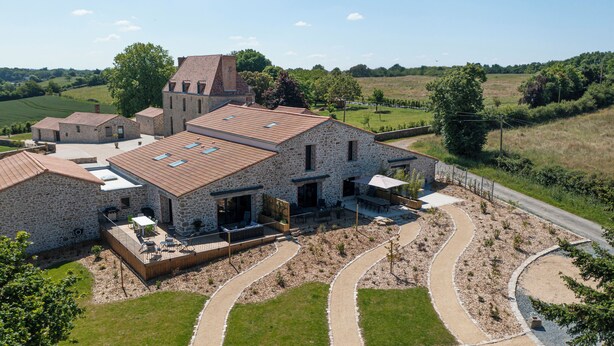 A stone house with a large patio, a separate kitchen area, and a small church in the background. - Le Domaine de la Haye - Group gîte for 16 people - 15 minutes from Puy du Fou (Saint-Christophe-du-Bois)