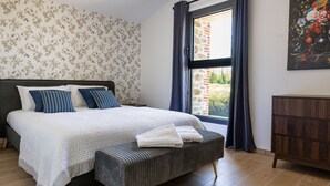 A bedroom with a bed, a bench, a dresser, a window with curtains, and a floral wallpaper. - Le Domaine de la Haye - Group gîte for 16 people - 15 minutes from Puy du Fou (Saint-Christophe-du-Bois)