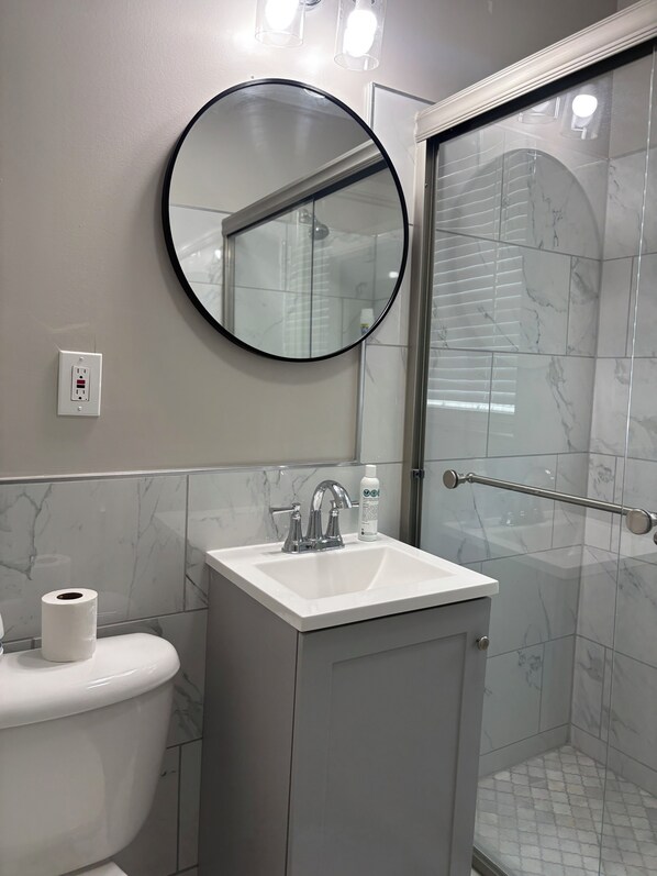 Une salle de bain équipée de toilettes, d’un lavabo, d’un miroir et d’une douche.