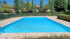 A rectangular swimming pool with a clear blue water surface, surrounded by a paved deck and bordered by neatly trimmed hedges and tall trees. - Superb studio in secure residence with swimming pool (Gagnac-sur-Garonne)