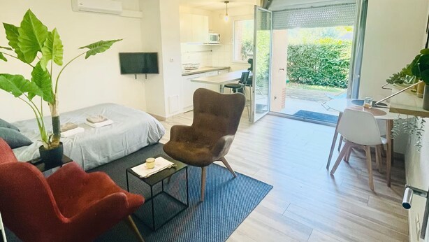 A modern living room with a sofa, armchair, and a dining area with a table and chairs. - Superb studio in secure residence with swimming pool (Gagnac-sur-Garonne)