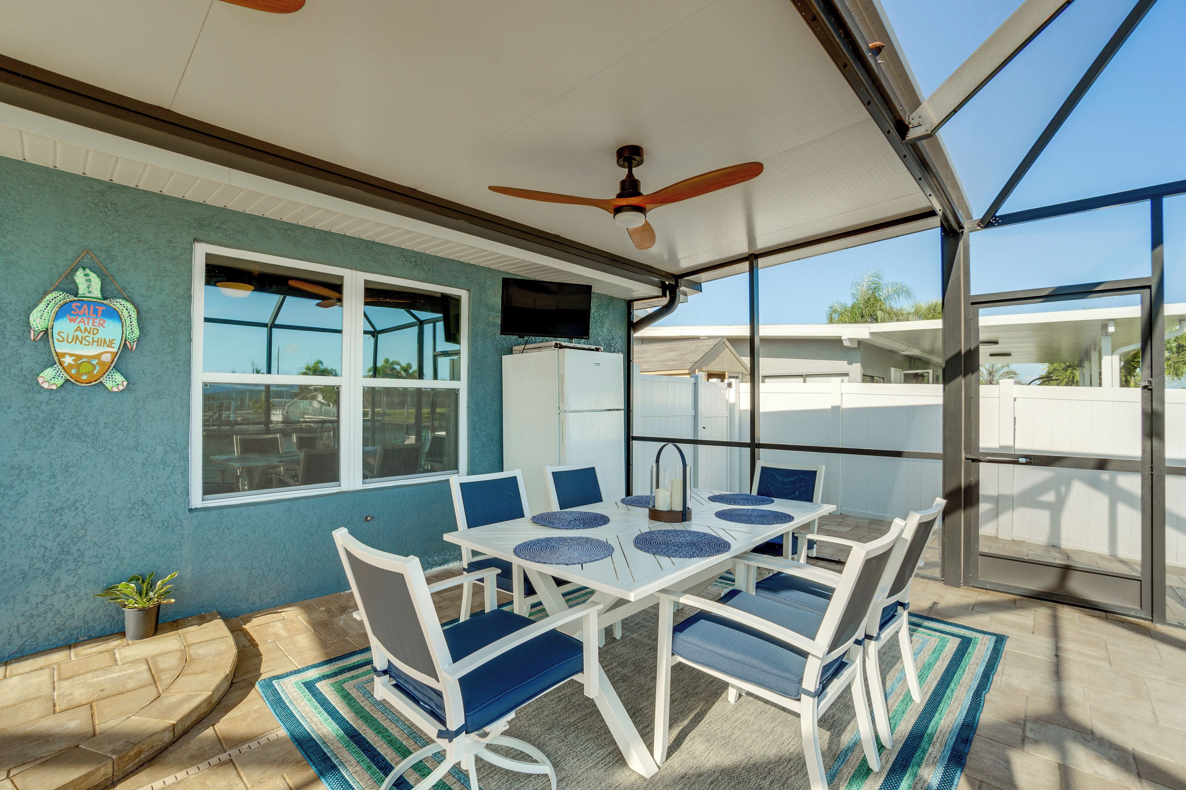 A covered patio with a table and chairs, a ceiling fan, and a view of the outside.