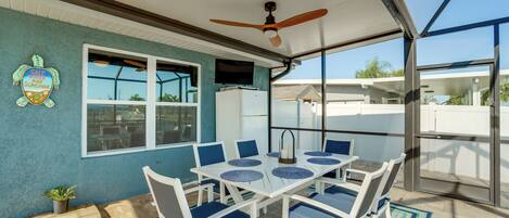A covered patio with a table and chairs, a ceiling fan, and a view of the outside.