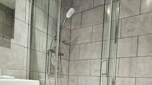 A modern bathroom with a glass-enclosed shower, a toilet, and a sink.